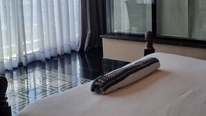 A hotel room with a large bed, a window with sheer curtains, and a view of the cityscape. - The Residence Suite Hotel (Addis Ababa)