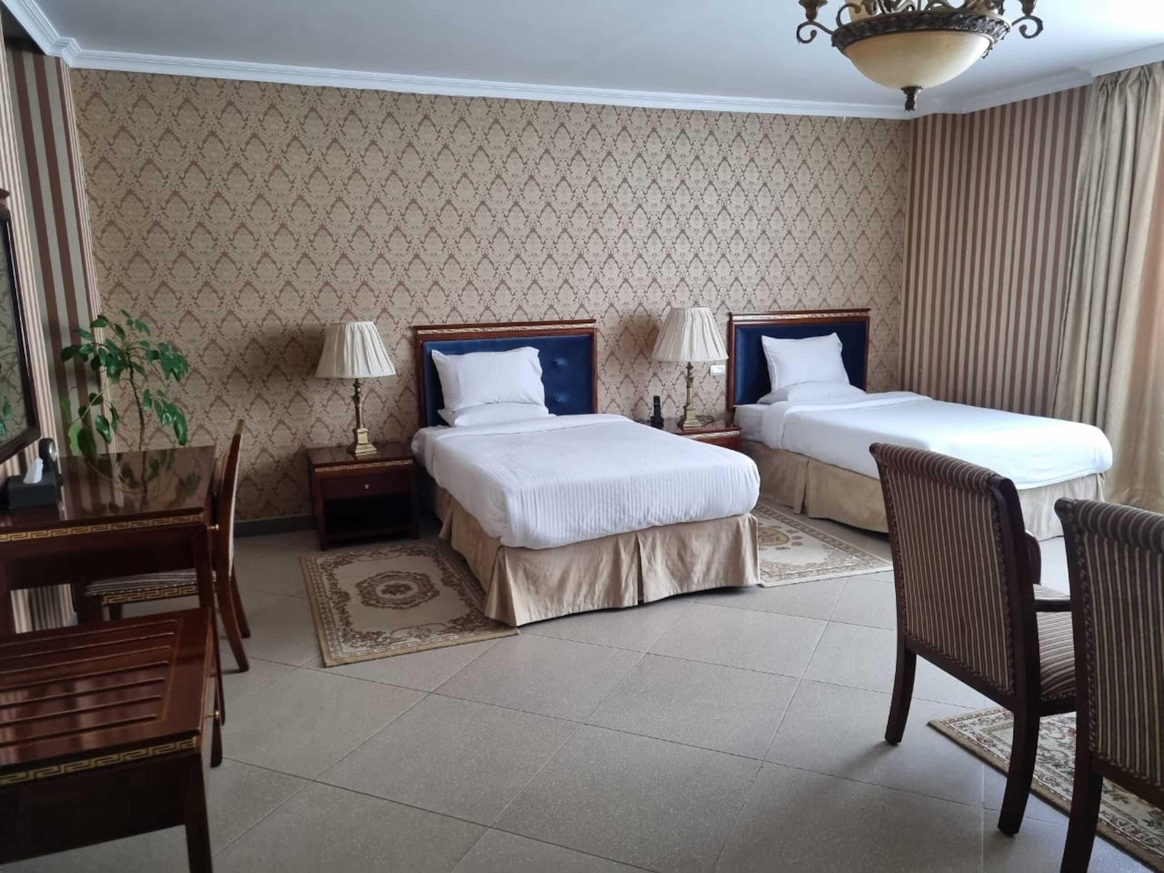 A hotel room with two beds, a desk, and a chair.