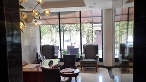 A modern lobby with a reception desk, seating area, and large windows offering views of the outdoors. - The Residence Suite Hotel (Addis Ababa)