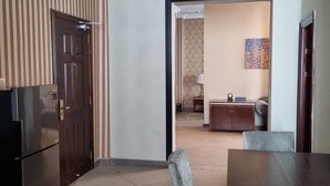 A modern kitchen with a refrigerator, a dining table with chairs, and a striped wallpaper wall. - The Residence Suite Hotel (Addis Ababa)