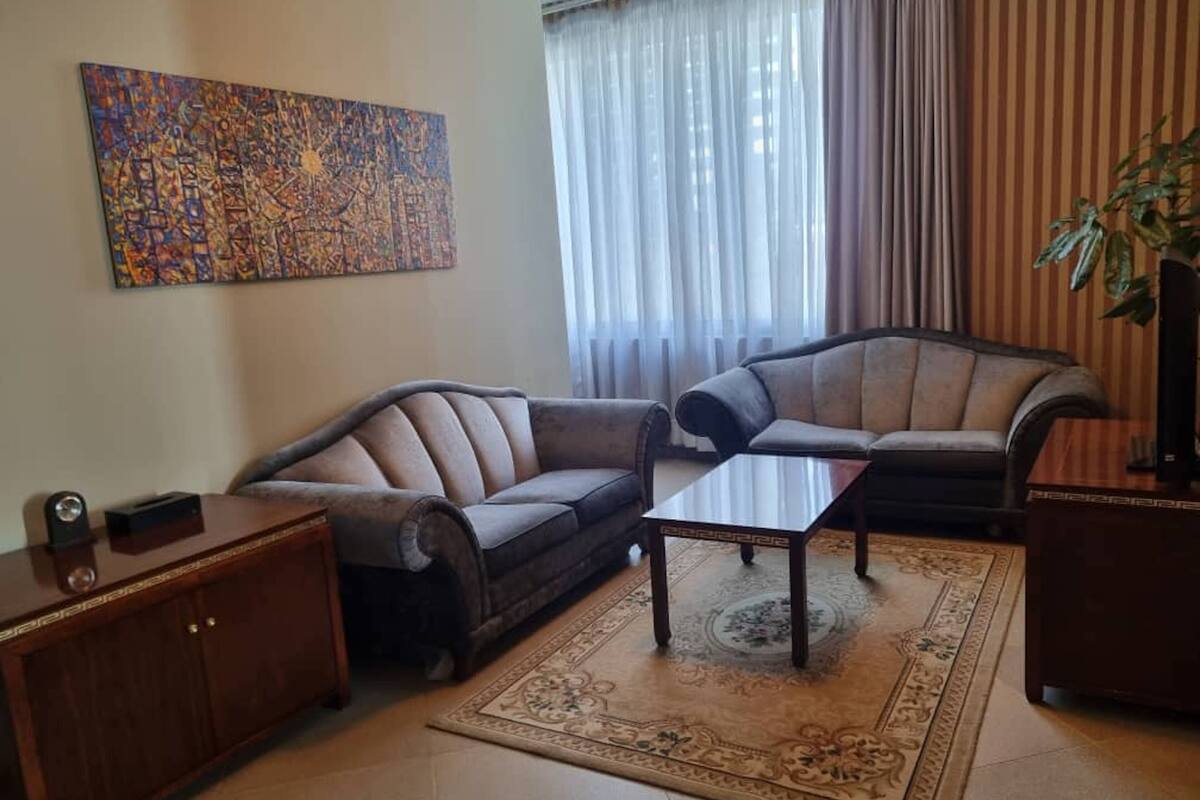 Uma sala de estar com dois sofás, uma mesa de centro, um armário e um quadro na parede.