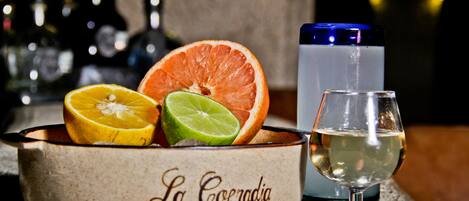 A bar setting with a citrus fruit display, a glass of white wine, and a blue cocktail glass.