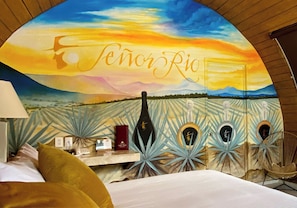 A room with a mural of a sunset and the text 'Señor Rio' on the wall. - Matices Hotel de Barricas (Tequila)
