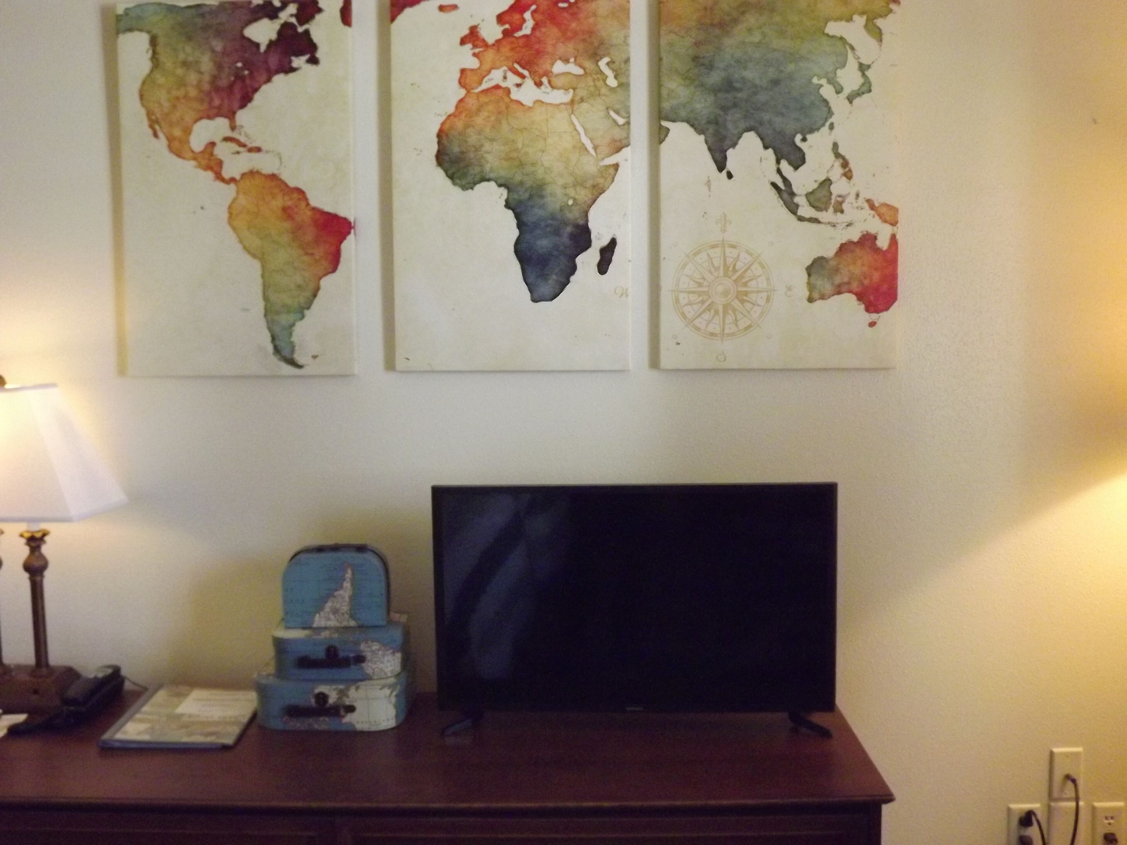 Un escritorio con una televisión de pantalla plana, una lámpara y un adorno pequeño.