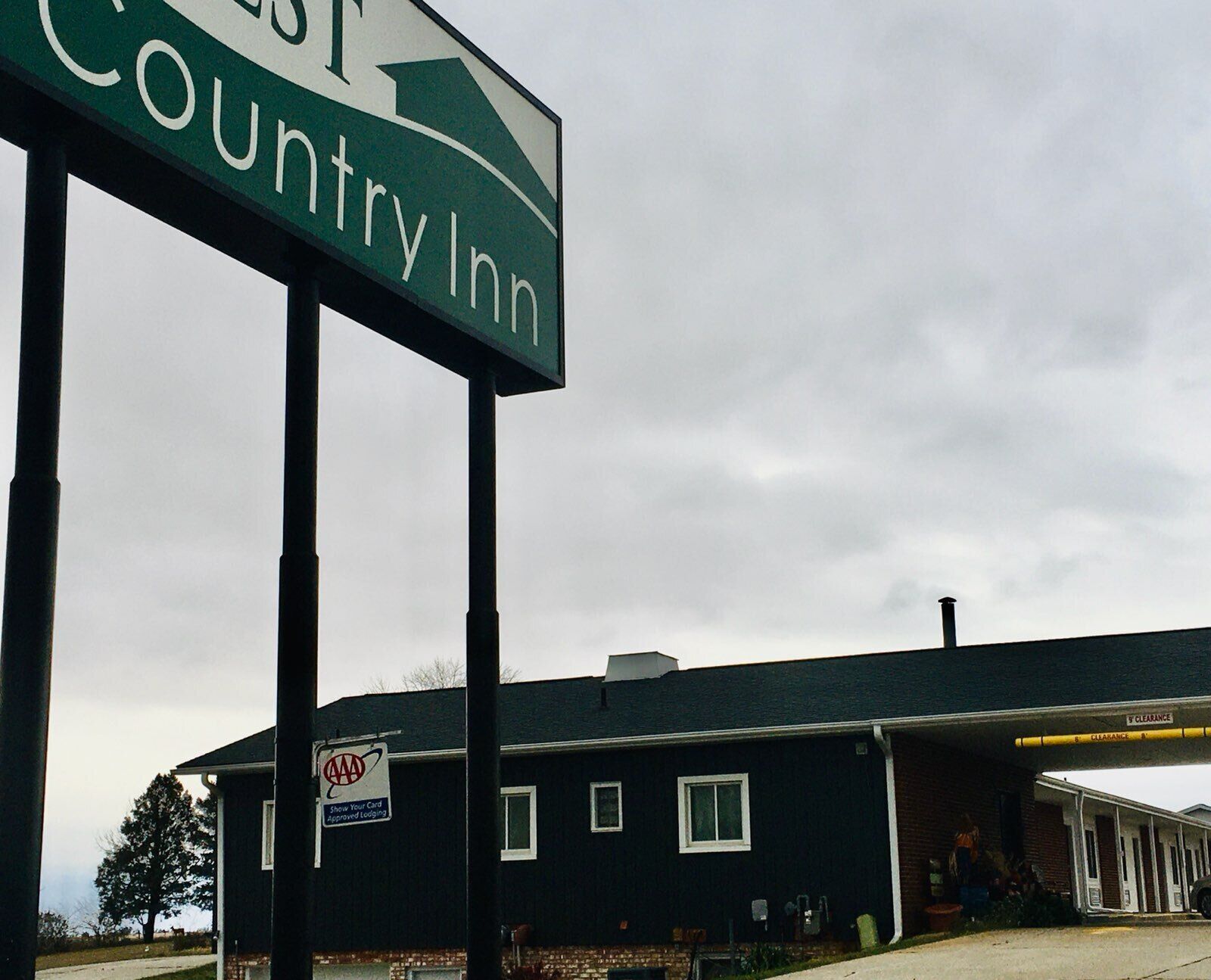 A Country Inn sign with a directional arrow, a AAA Approved logo, and a building with a covered parking area.