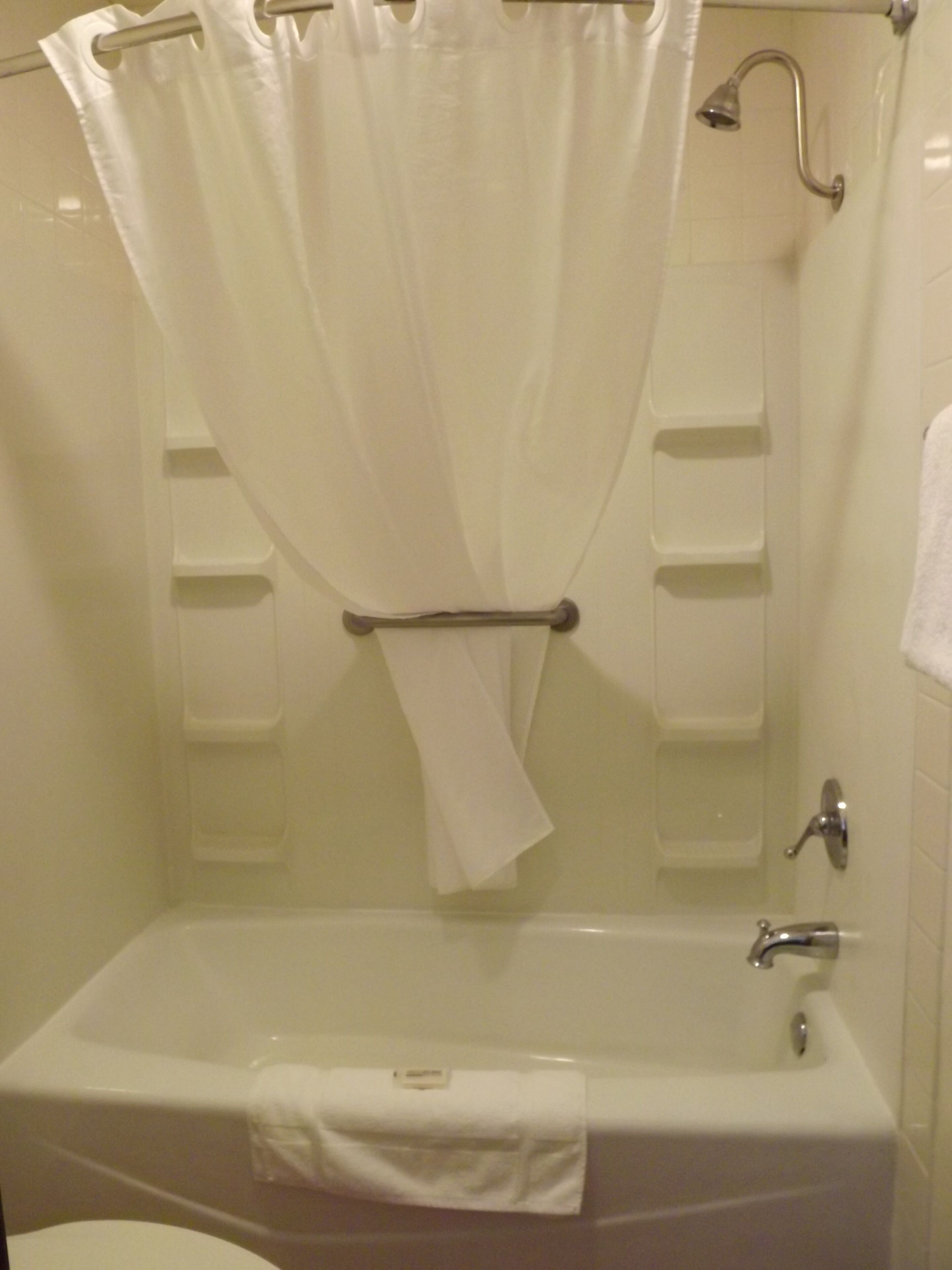 A bathroom with a bathtub, a shower curtain, and a towel rack.