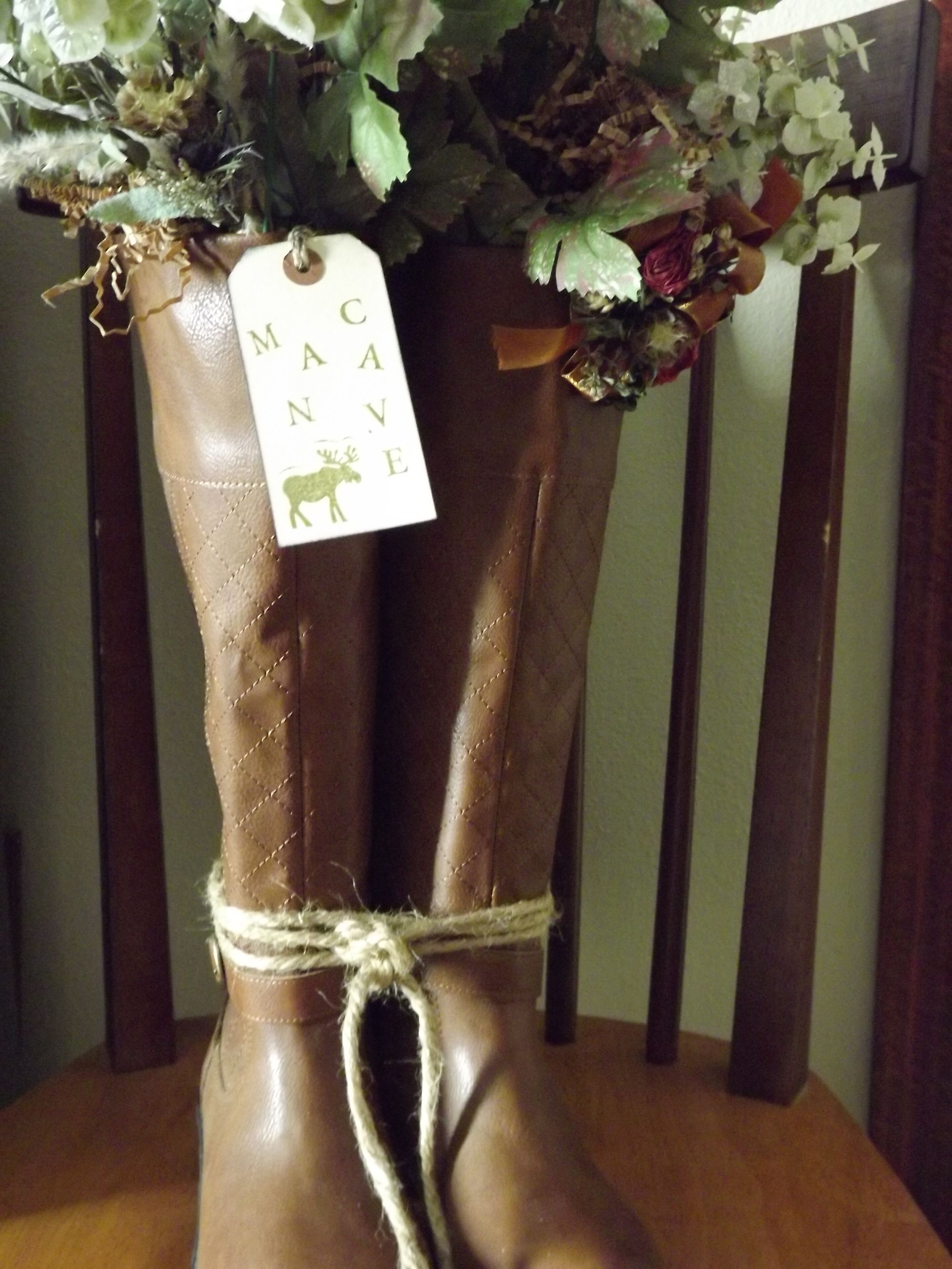 A pair of brown leather boots with a tag reading "MACAVE" and a rope tied around the ankle.