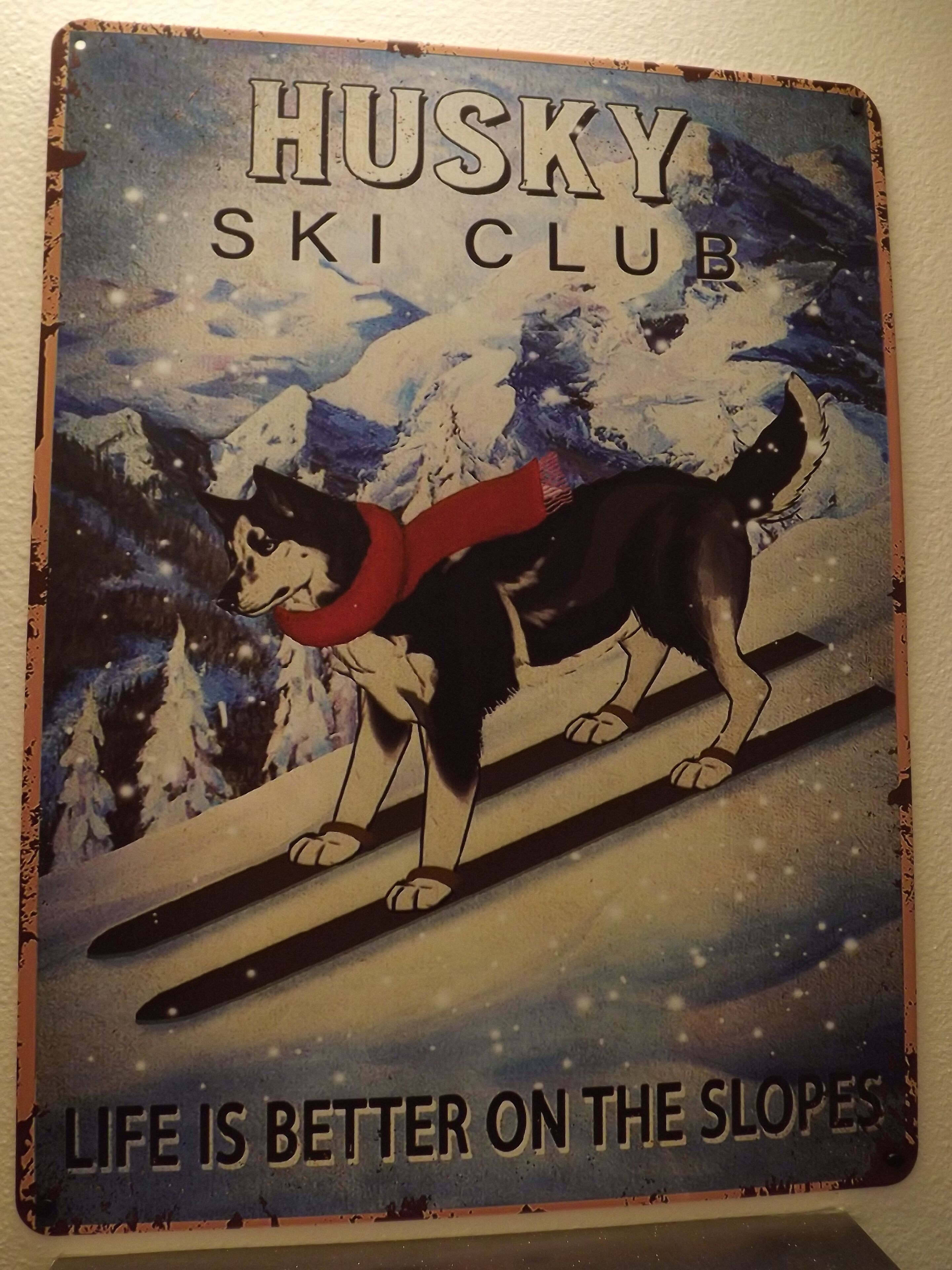 A sign for Husky Ski Club with a dog on skis and the text "Life is better on the slopes."