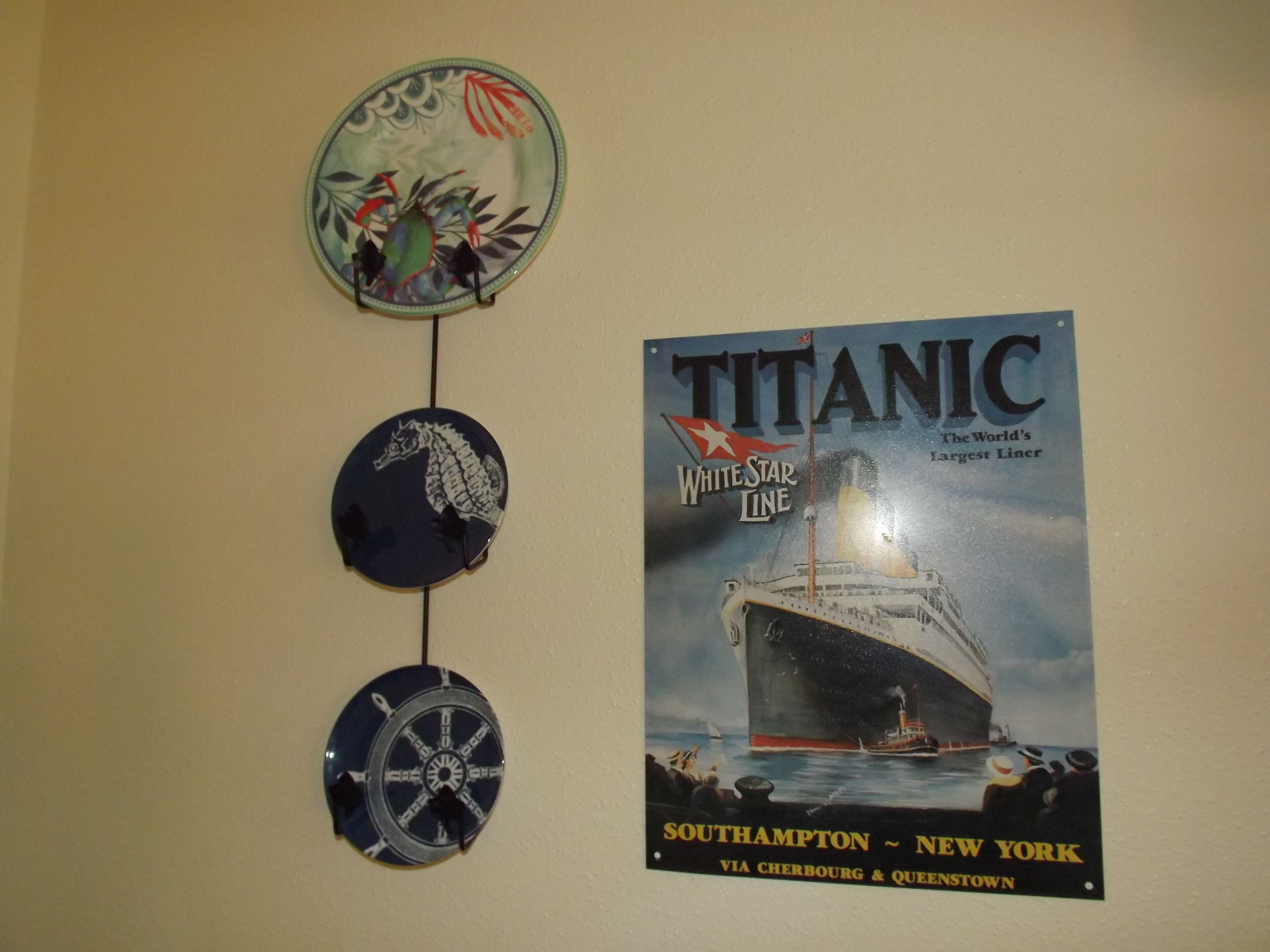A wall with a poster of the Titanic and three nautical-themed wall hangings.
