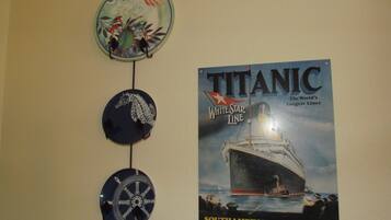 A wall with a poster of the Titanic and three nautical-themed wall hangings.