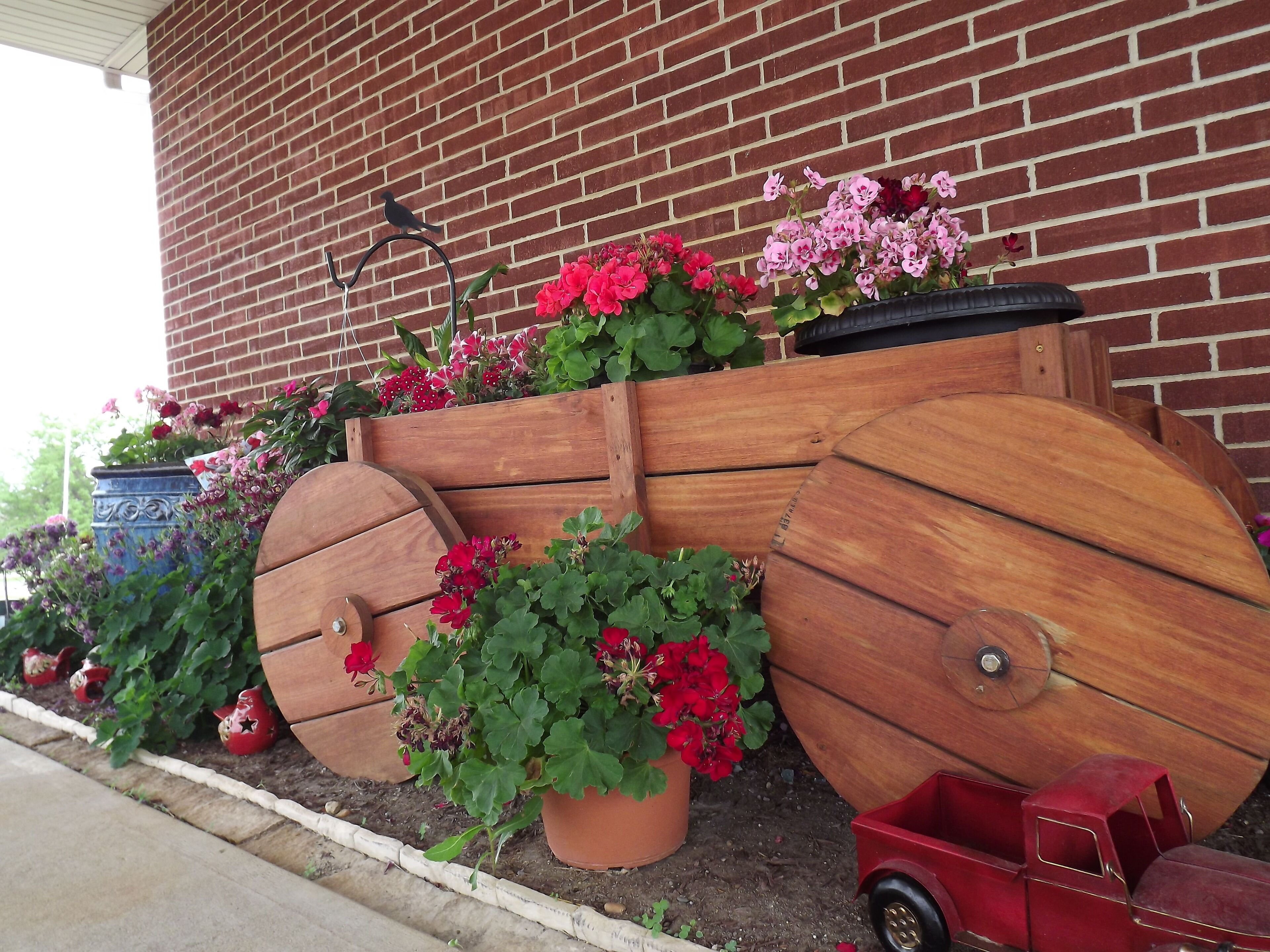 A garden bed with wooden planters and flowers against a brick wall.