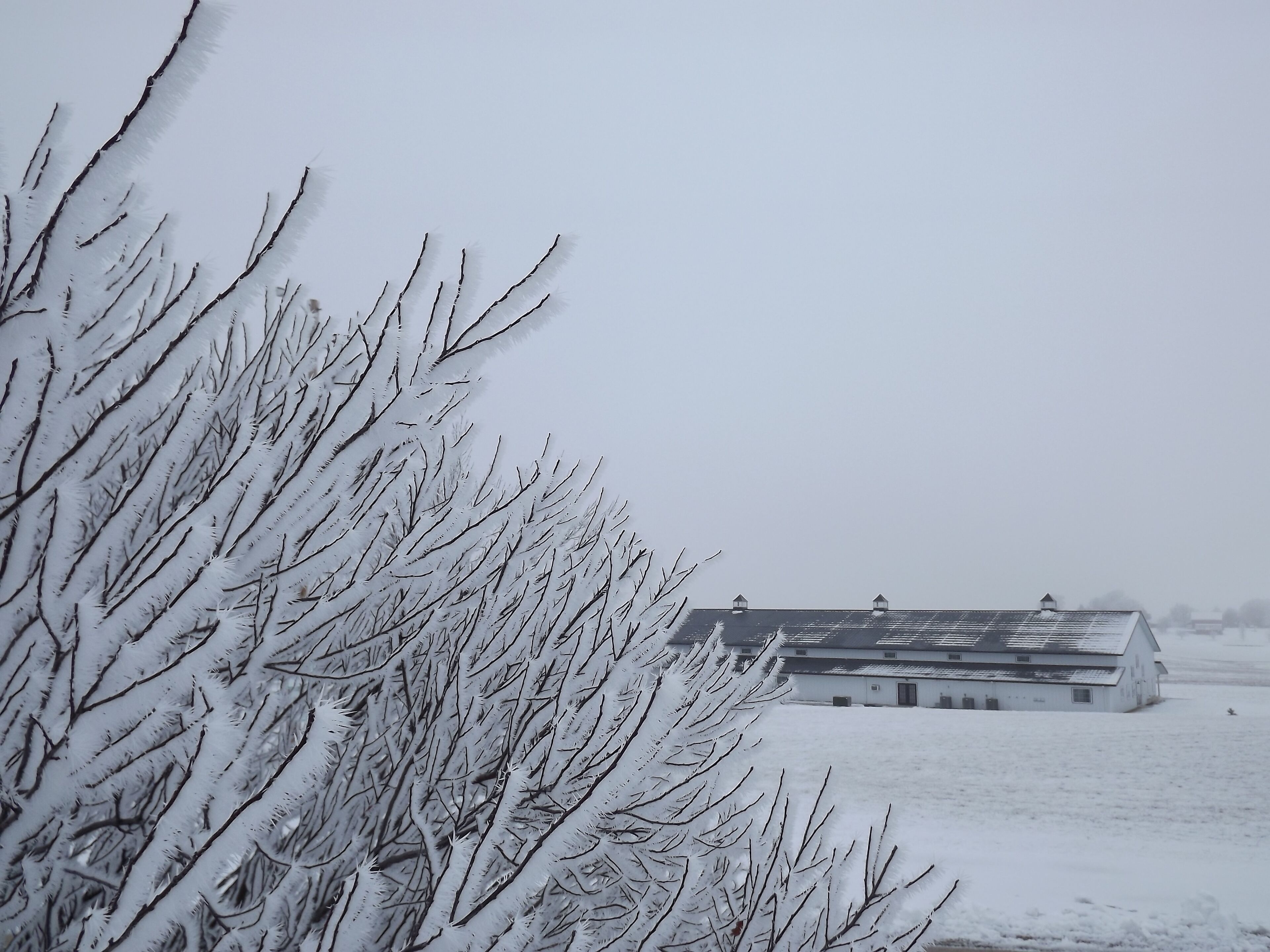 A snow-covered landscape with a building that has a flat roof and multiple chimneys.