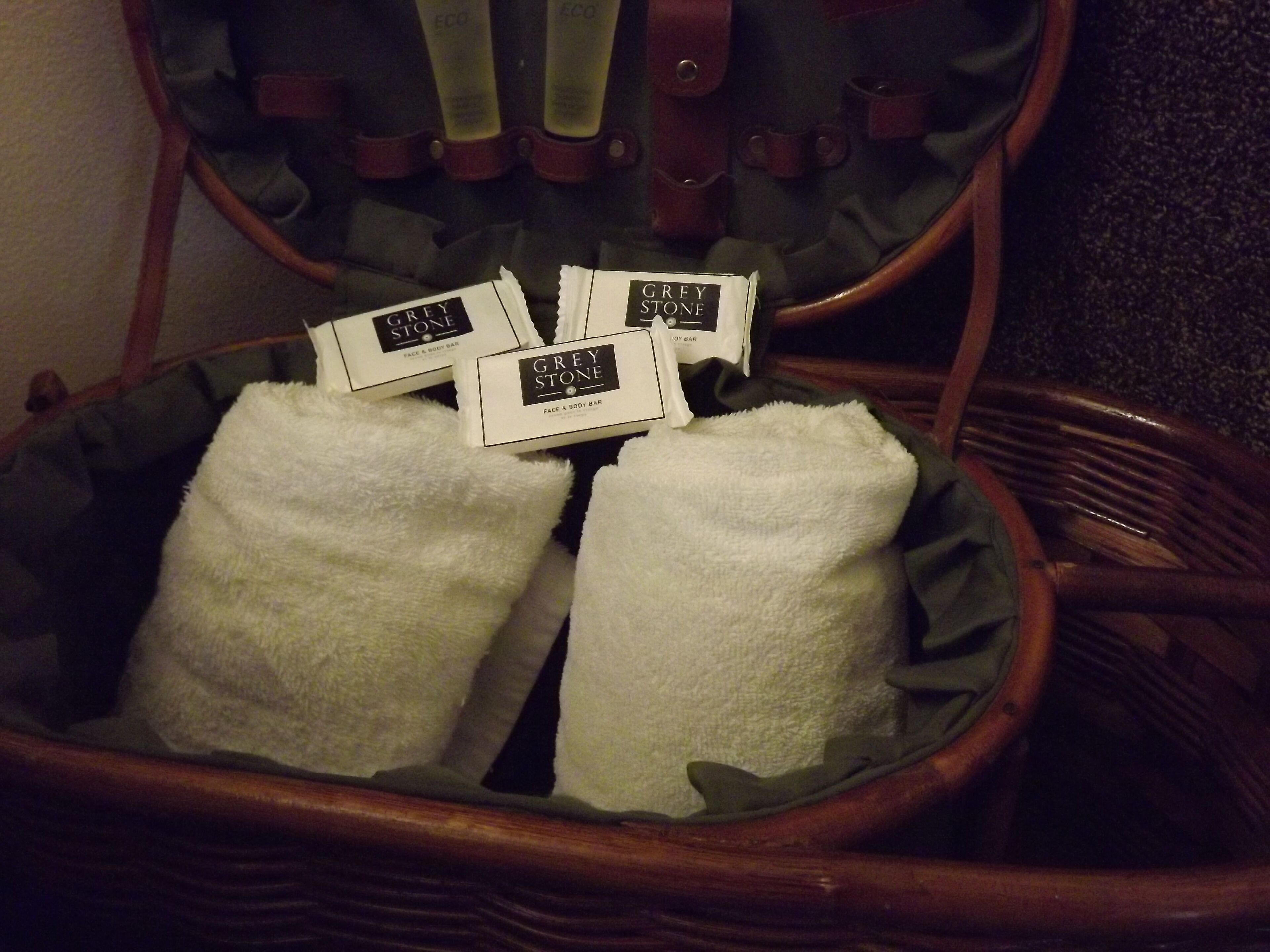 A wicker chair with a white towel and Grey Stone face & body bar products.