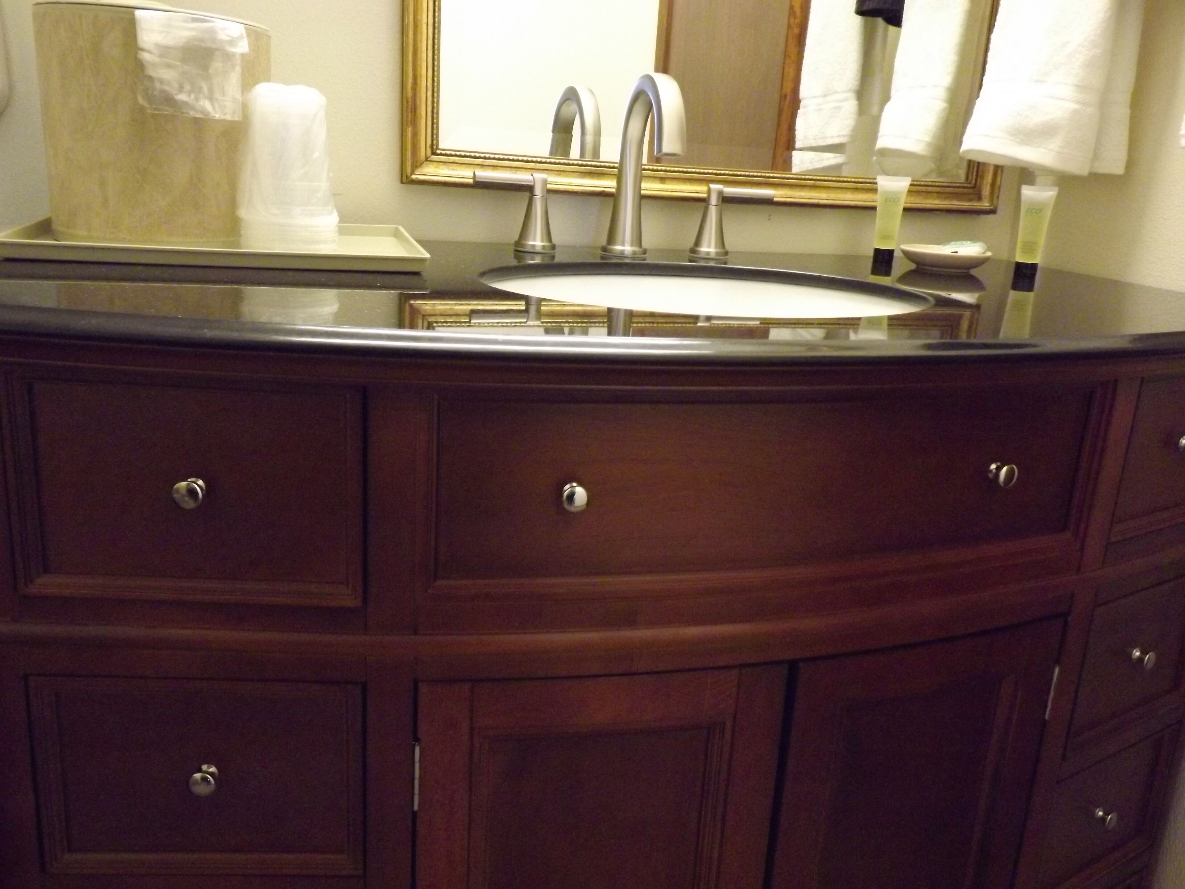 A bathroom vanity with a sink, mirror, and multiple drawers.
