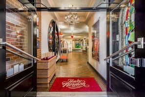 Una entrada de hotel con alfombra roja, una escalera y un muro de ladrillo.