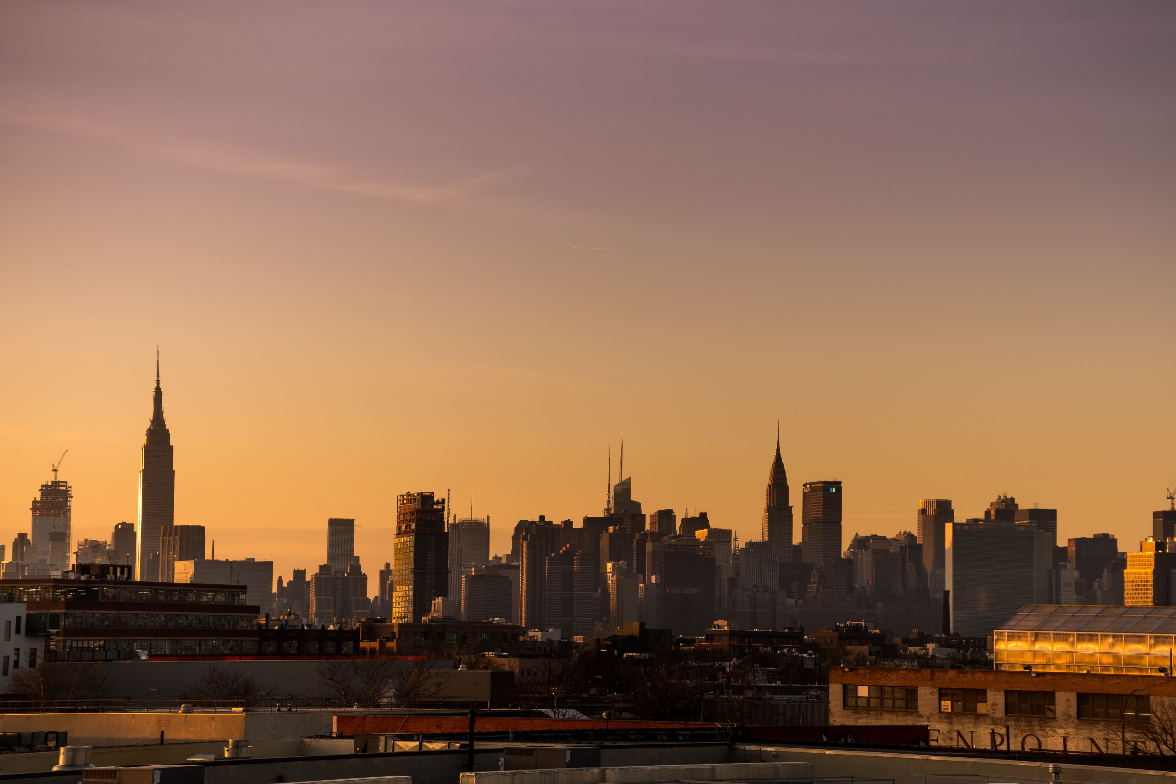 Horizonte urbano ao pôr do sol, com arranha-céus imponentes e uma mistura de edifícios modernos e antigos.