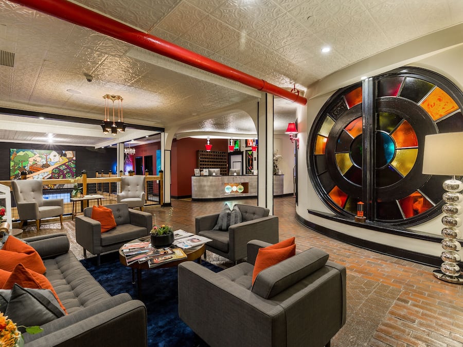 A spacious lobby with a modern design, featuring a large circular stained glass window, comfortable seating areas, and a reception desk.