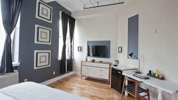 Une chambre d’hôtel moderne dotée d’un grand lit, d’un bureau avec un ordinateur, d’une télévision à écran plat et d’une fenêtre avec des rideaux.