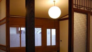 Ett traditionellt japanskt rum med tatamimattor på golvet, skjutdörrar och en hängande lampa.