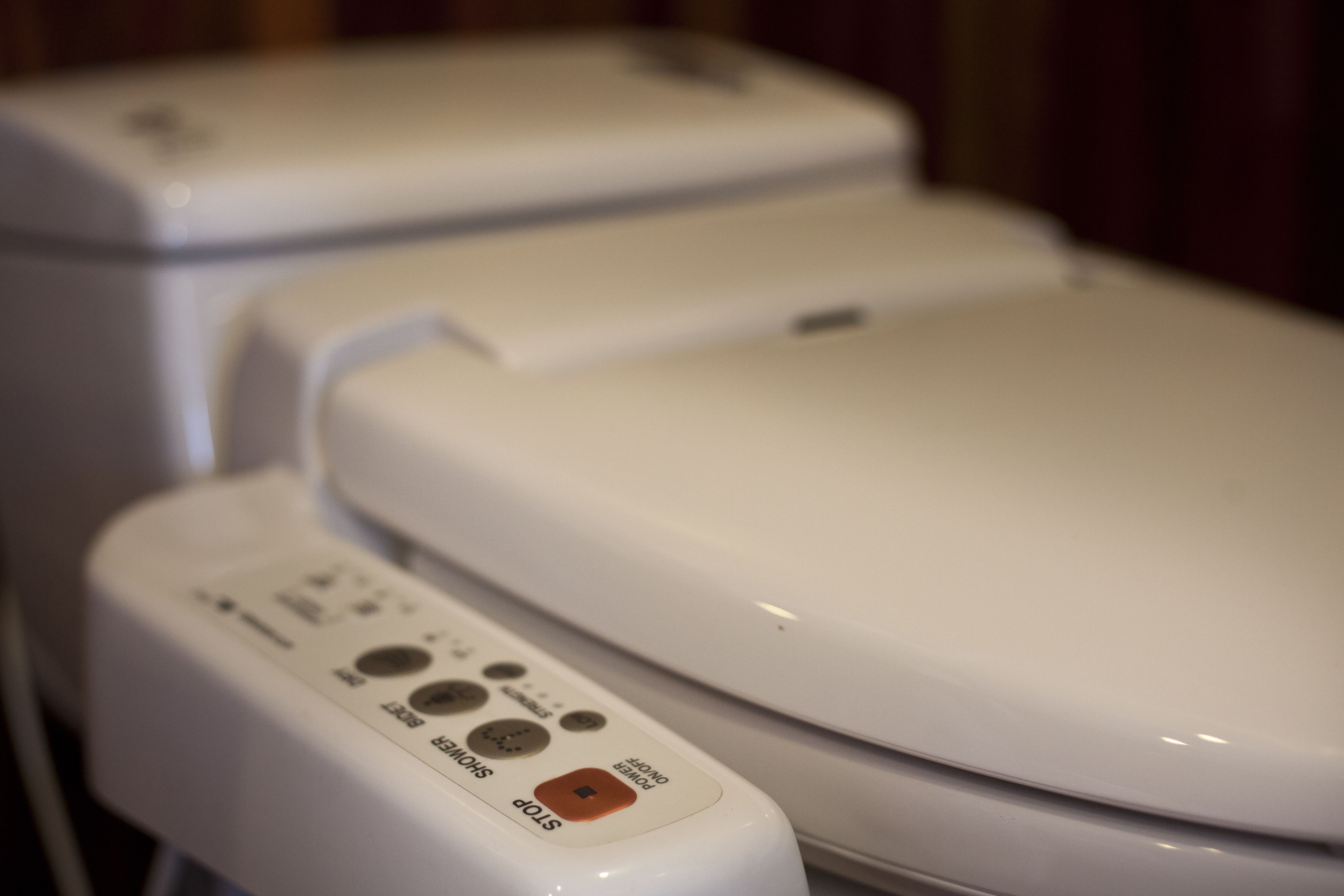 A white toilet with a control panel featuring buttons labeled "START," "STOP," and "POWER."