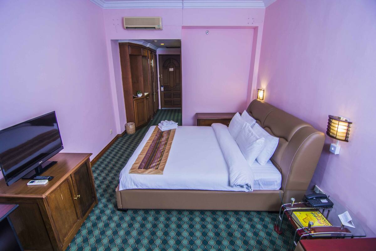 Une chambre d’hôtel équipée d’un lit, d’une télévision, d’un bureau et d’une table de chevet.
