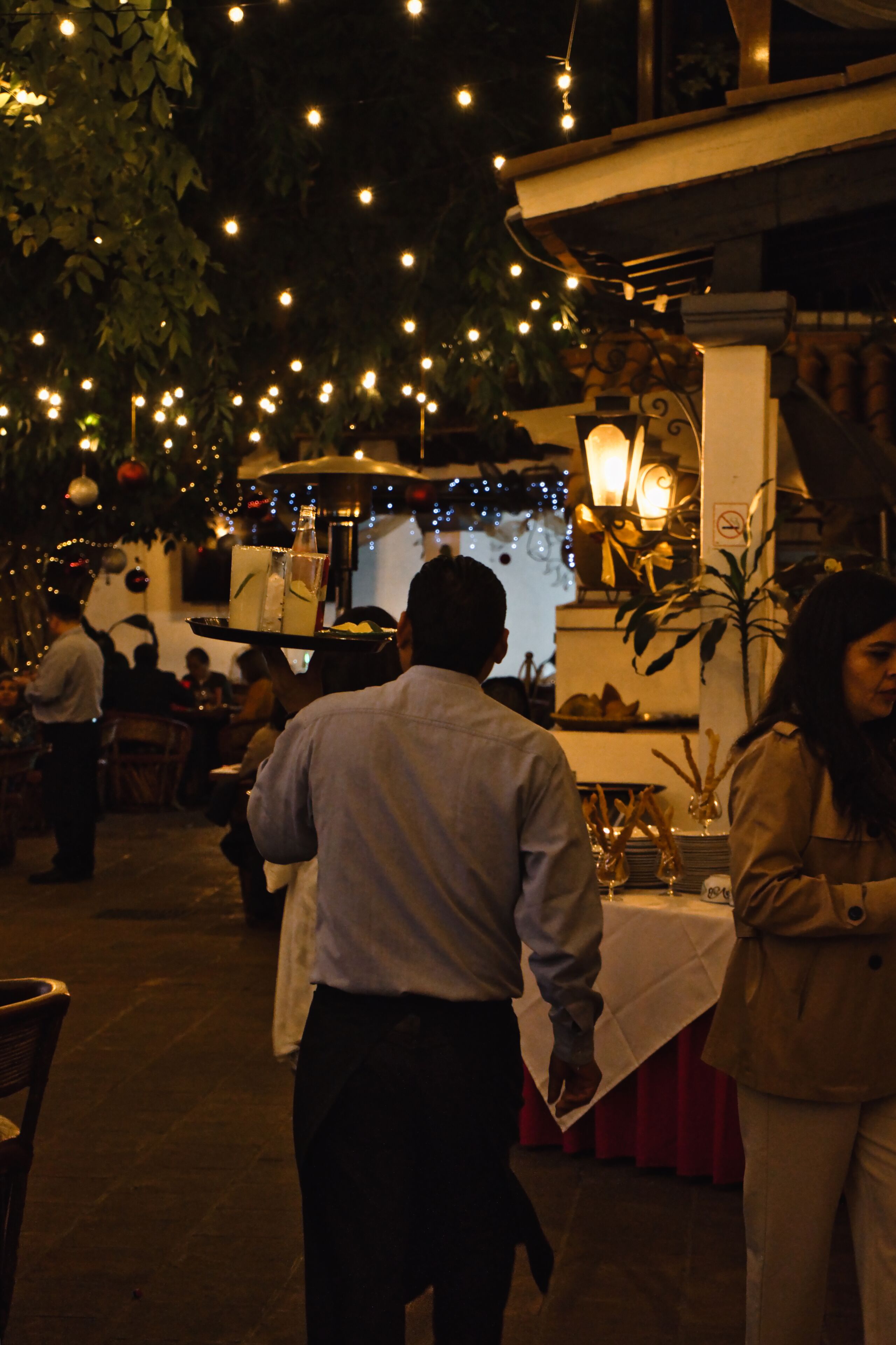An outdoor dining area with string lights, tables, and chairs.