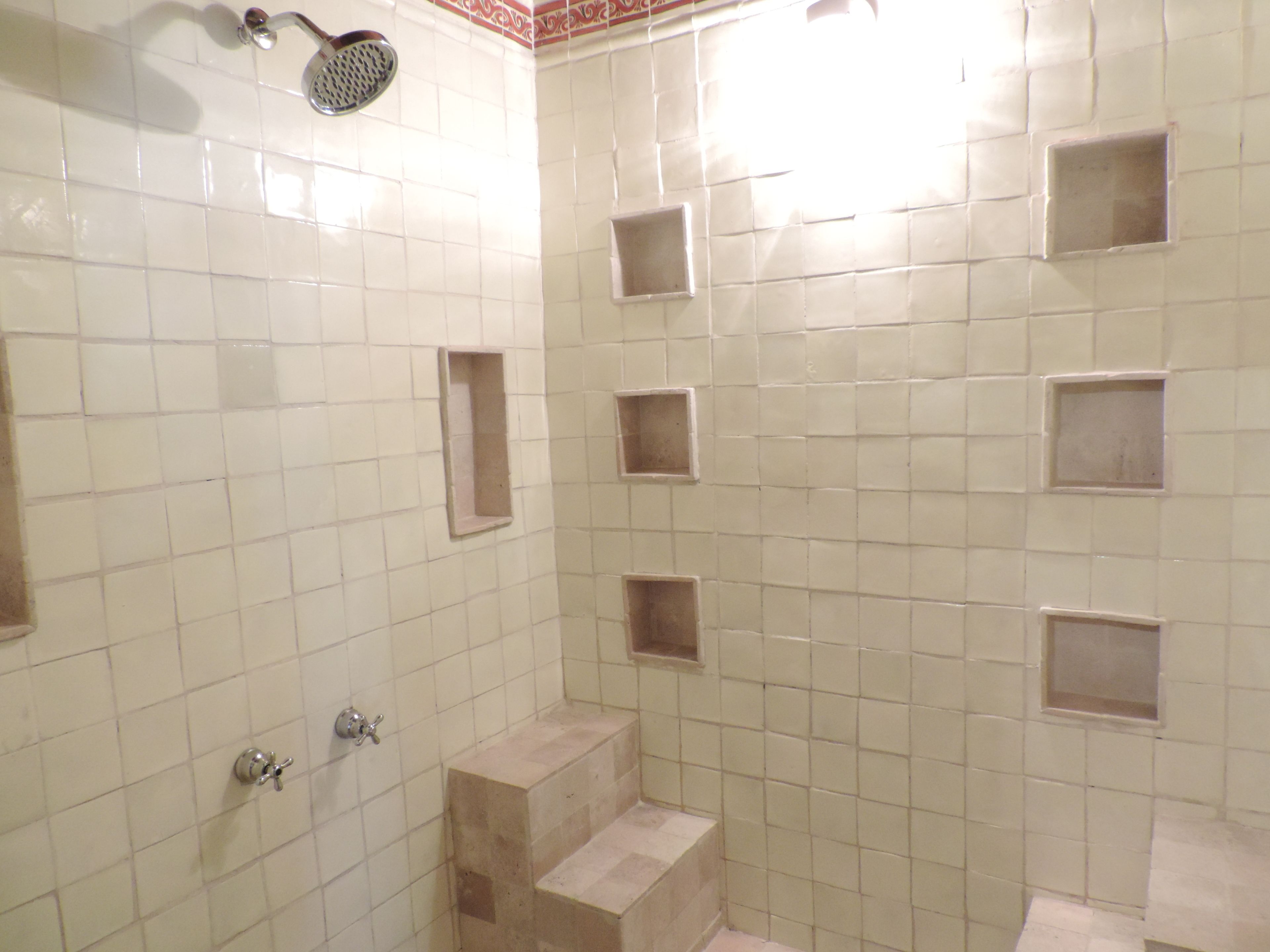 Un espacio de ducha con azulejos, un cabezal de ducha de mano y un grifo empotrado en la pared.