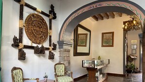 Una habitación con muebles de madera antiguos, chimenea de piedra y un espejo.