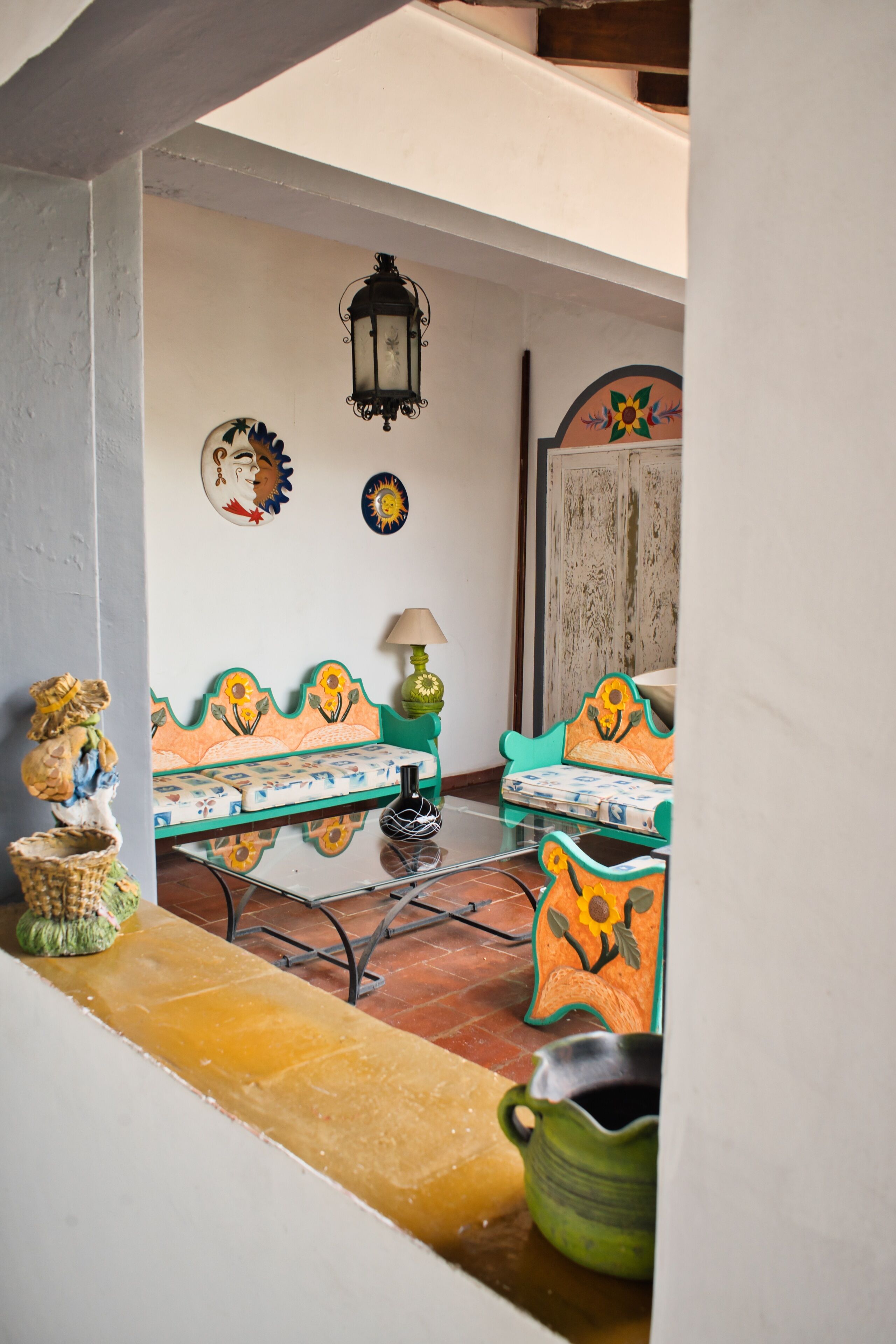 A cozy outdoor seating area with a table and chairs, a lamp, and decorative plates on the wall.