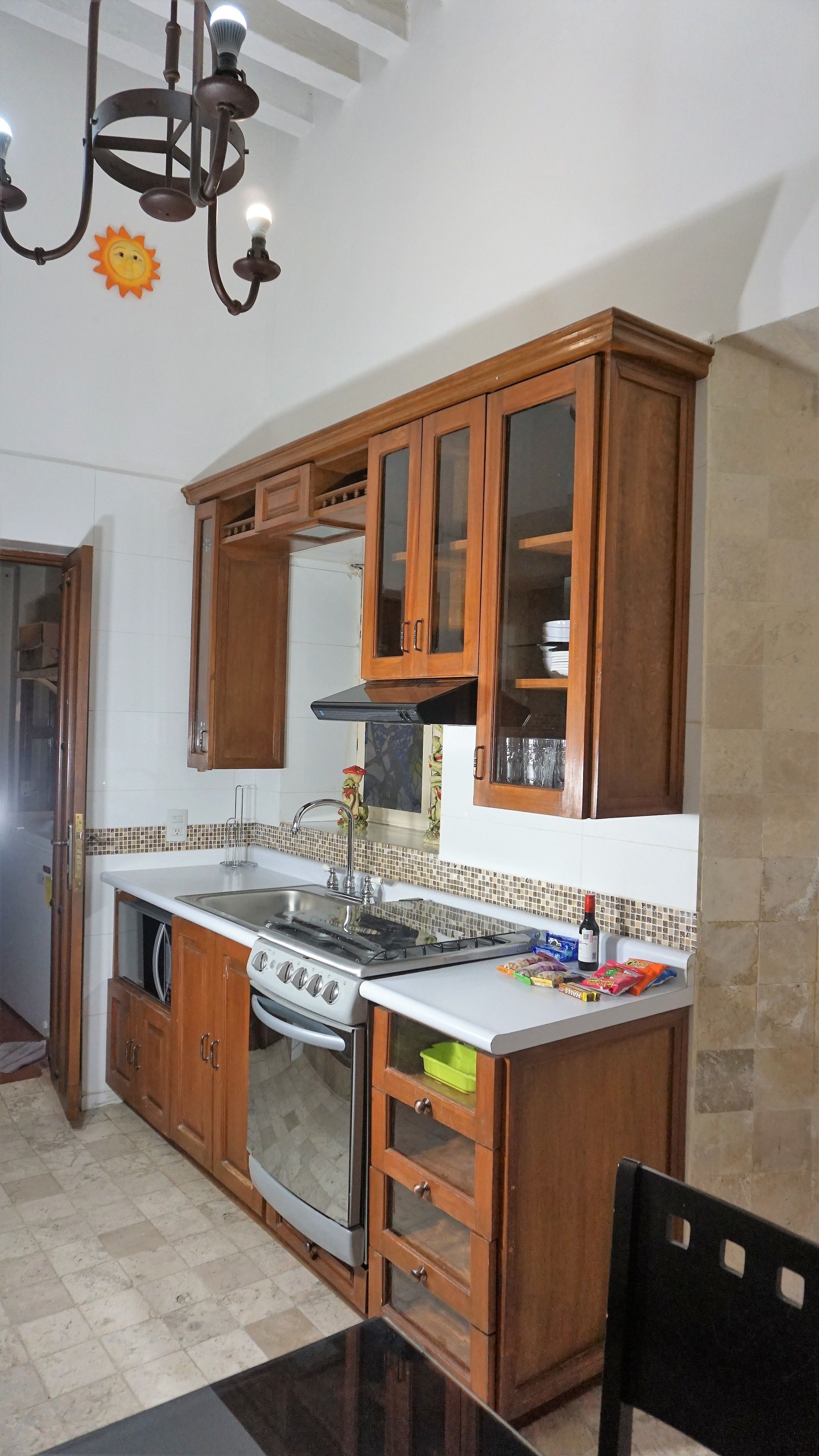 A kitchen with wooden cabinets, a stove, a sink, and a chandelier.