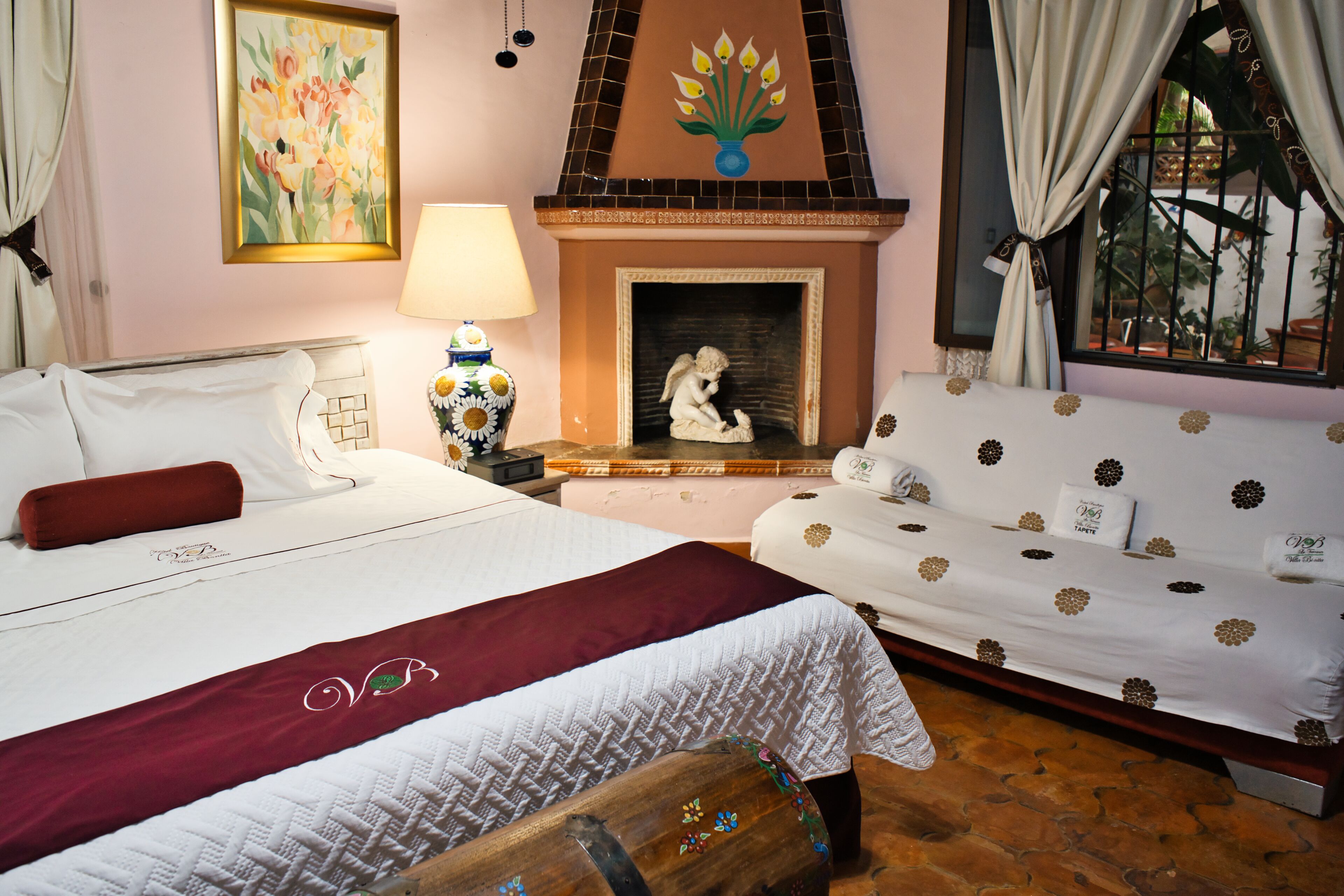 Un dormitorio con cama, sofá, chimenea y ventana con cortinas.