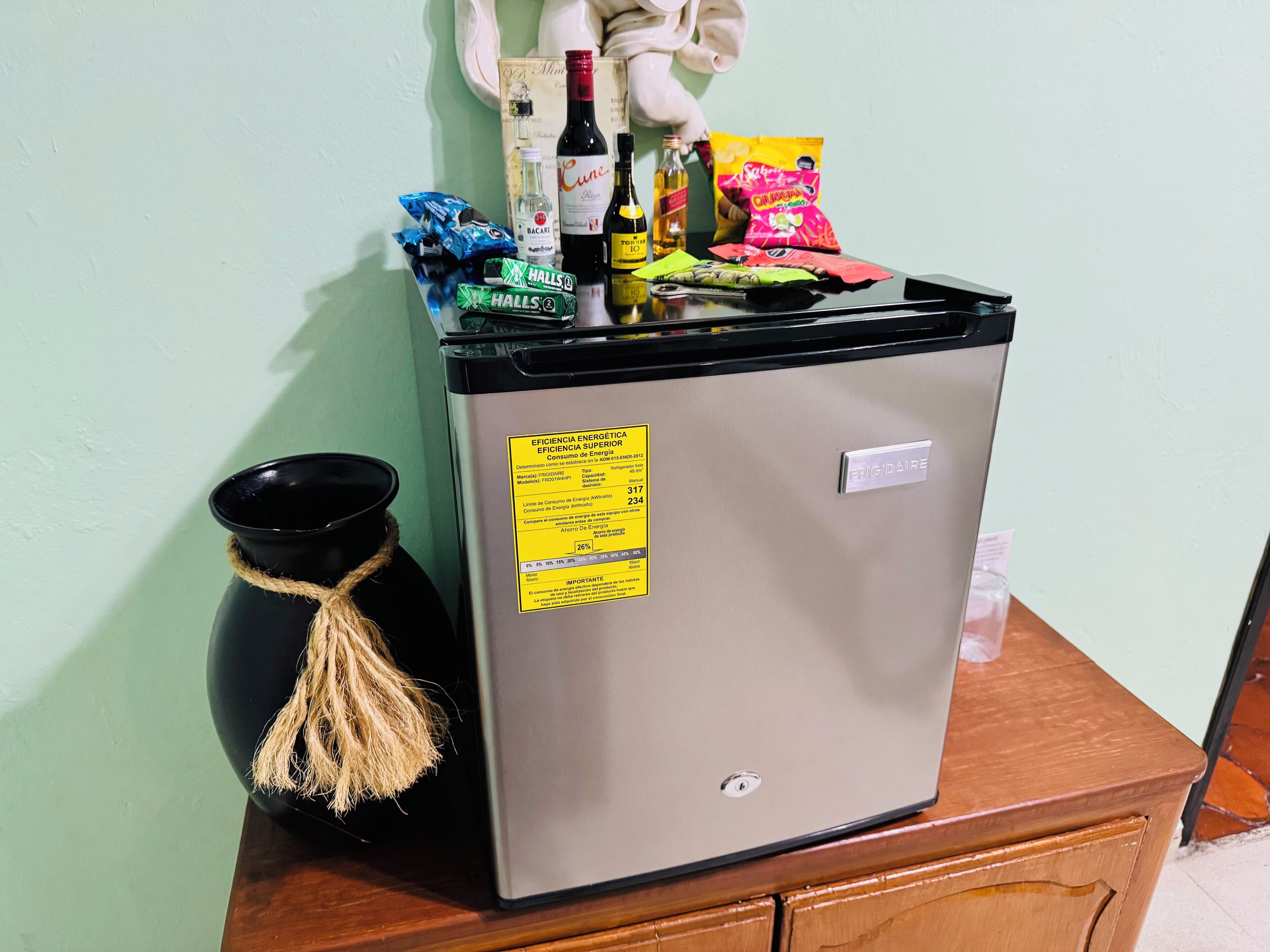 A compact refrigerator with a sticker indicating energy efficiency, placed on a wooden cabinet.