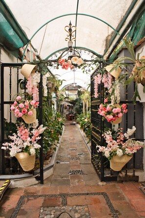 Un pasillo cubierto con arreglos florales colgantes y plantas en macetas a ambos lados.