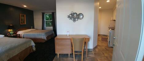 Quarto de hotel com duas camas, uma mesa de trabalho e uma kitchenette.