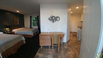Una habitación de hotel con dos camas, un escritorio y una kitchenette.