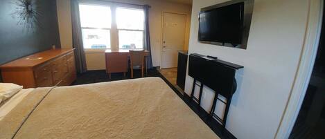 Ein Hotelzimmer mit einem Bett, einem Schreibtisch, einem Stuhl, einem Fernseher und einer Kommode.
