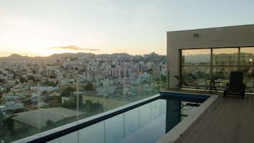 Ein modernes Gebäude mit Glasbalkon mit Blick auf eine Stadtlandschaft bei Sonnenuntergang.
