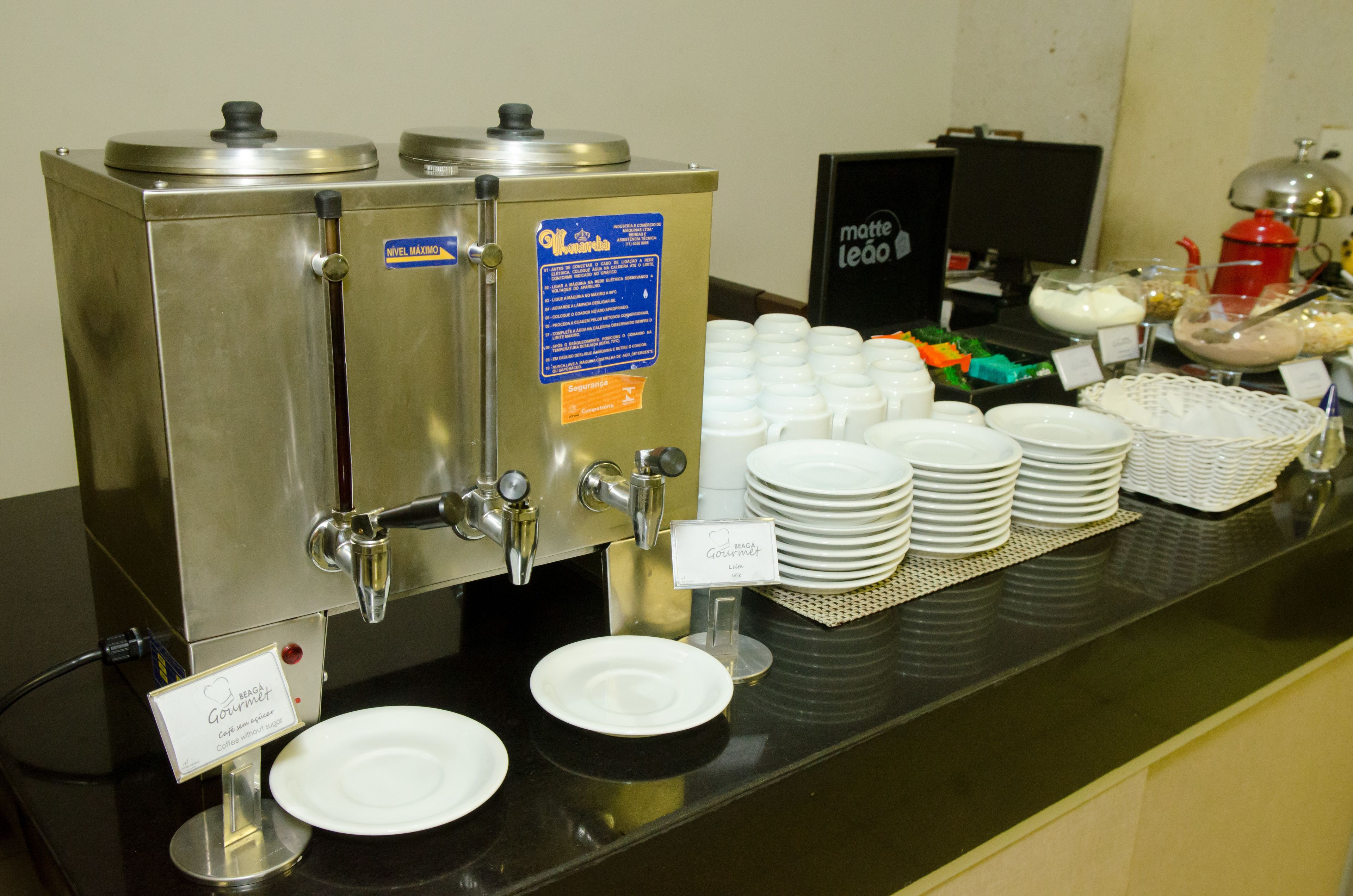 Montaje de bufé con dispensadores de café, platos y un cartel que dice 'Beach Gourmet'.