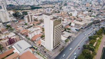 Un paisaje urbano con un edificio blanco destacado de varios pisos, rodeado de otros edificios y una calle concurrida con vehículos.