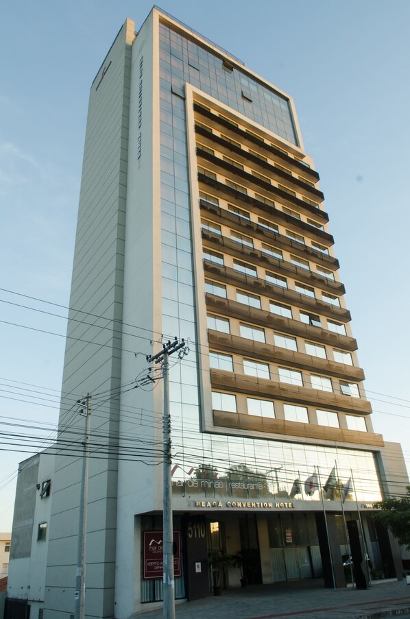Um hotel alto com fachada de vidro moderna, um restaurante no térreo e um letreiro de centro de convenções.