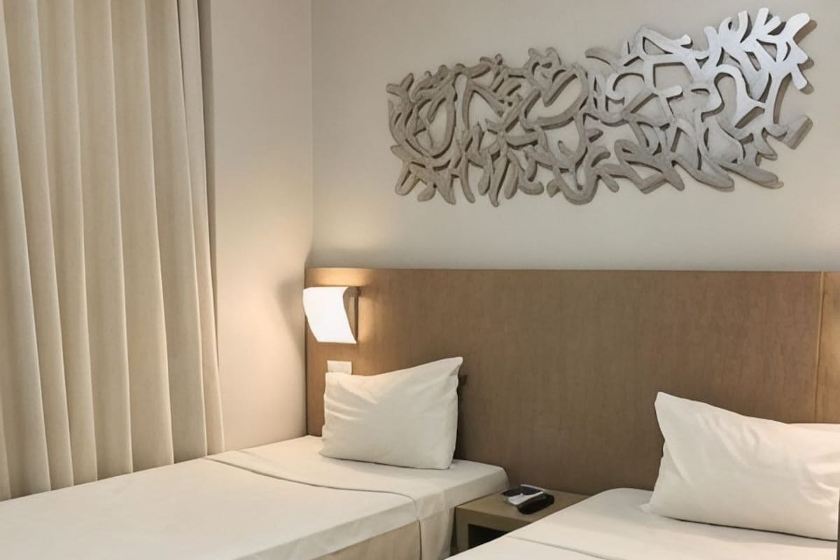 Ein Hotelzimmer mit zwei Betten, einer Wandleuchte und einem Wanddekor.