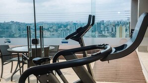 Un gimnasio con equipo de ejercicio y vistas a un paisaje urbano.