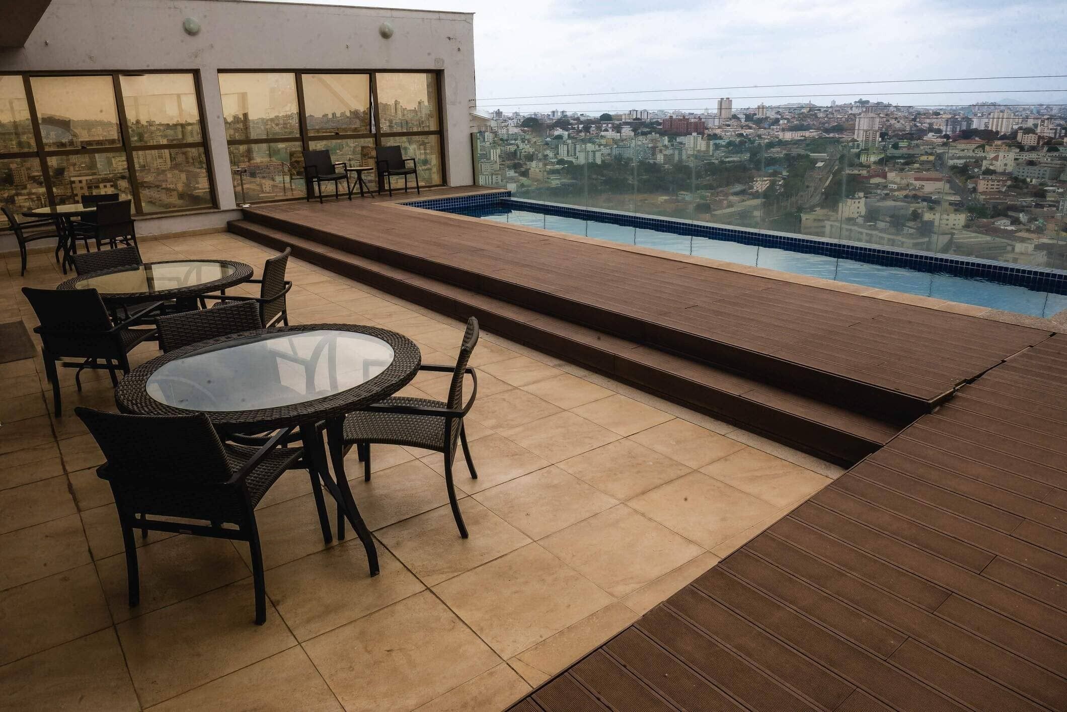 A rooftop terrace with a pool, outdoor seating, and a city view.