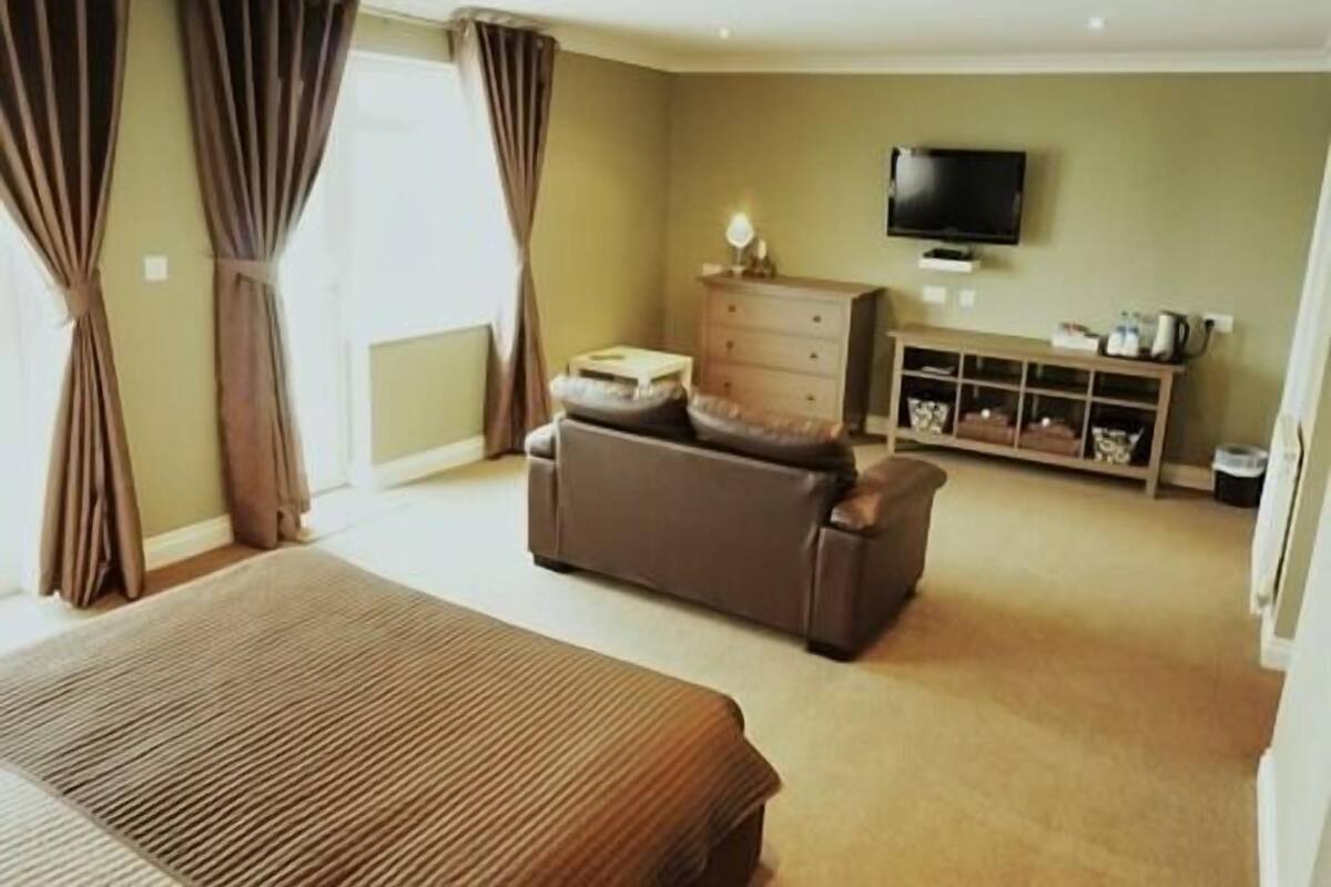 Un dormitorio con cama, sofá, televisor y cómoda.