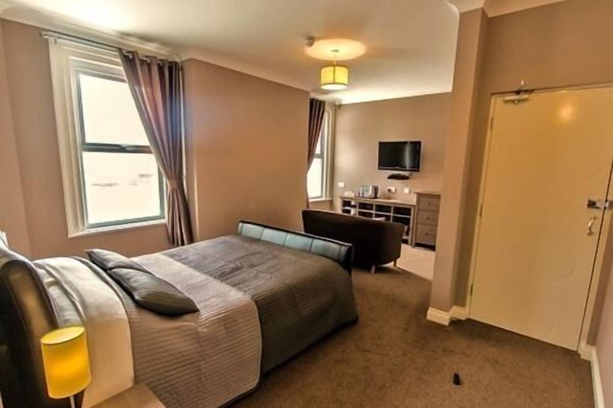Una habitación de hotel con cama, escritorio, silla, televisor y armario.