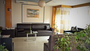 Una sala moderna con un sofá de cuero negro, una mesita de centro y una planta en maceta.