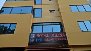 Un edificio de varios pisos con un letrero que indica Hotel Milina y Restaurante Shirasagi.