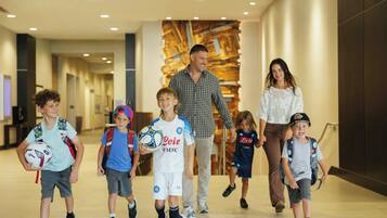 A group of people walking in a hallway with a modern interior design, including a wooden wall and recessed lighting.