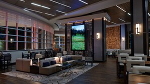 Un rebedor d'hotel modern amb una gran pantalla de televisió, seients confortables i una paret decorativa de fusta.