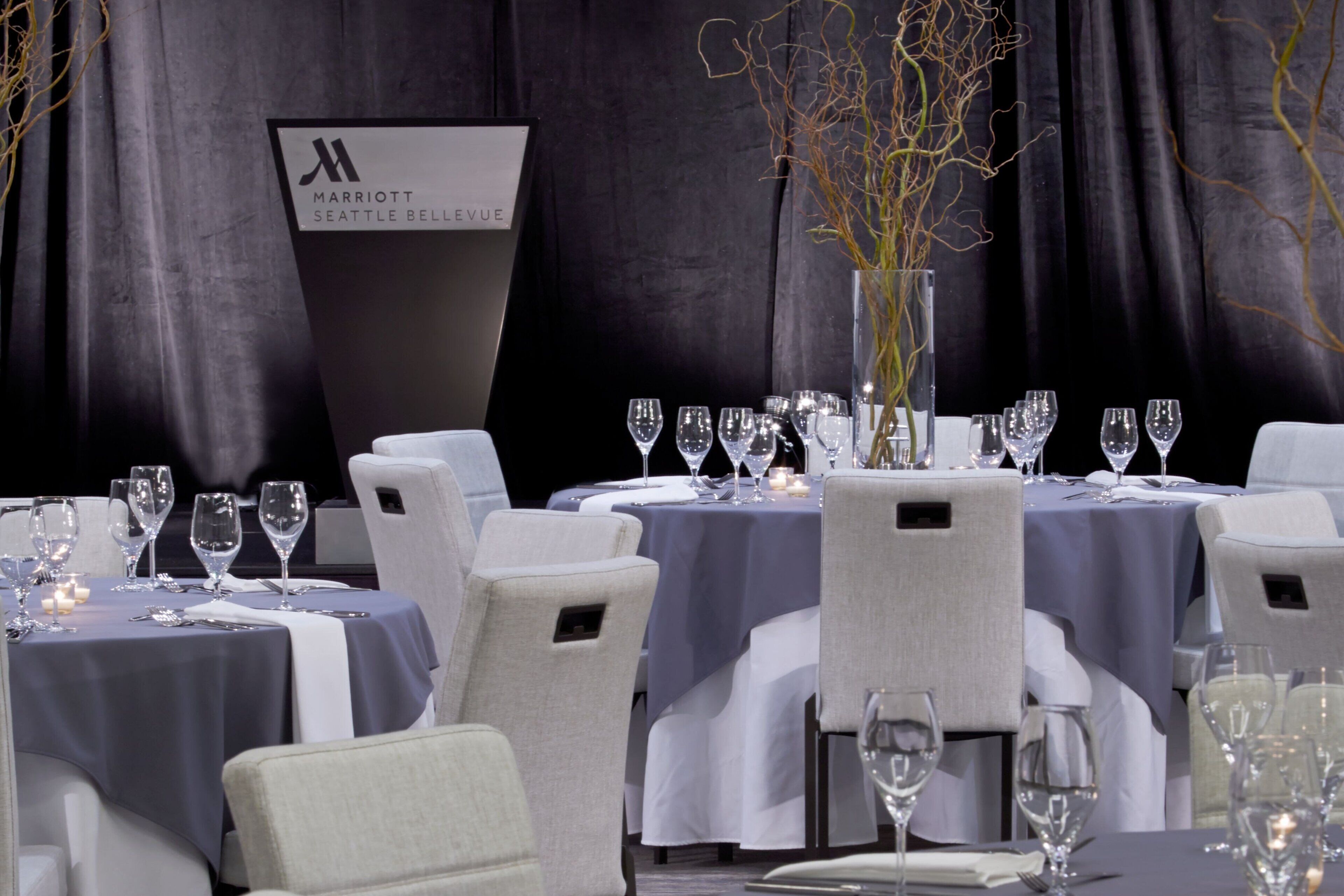A restaurant setting with tables set for dining, featuring a sign for Marriott Seattle Bellevue.